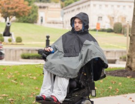 Adult wearing The Winter Cape by Abram's Nation in an electric wheelchair