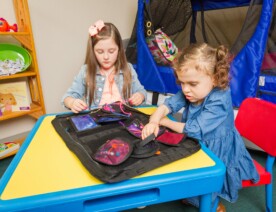 Two young children play with The Fidget Folder by Abram's Nation