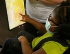 Student in a wheelchair looks and points to the iPad which is dislaying a yellow screen with a variety of yellow sparkling effects